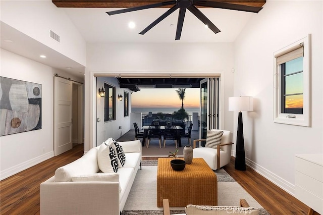 living room featuring vaulted ceiling, dark wood-type flooring, a barn door, and ceiling fan