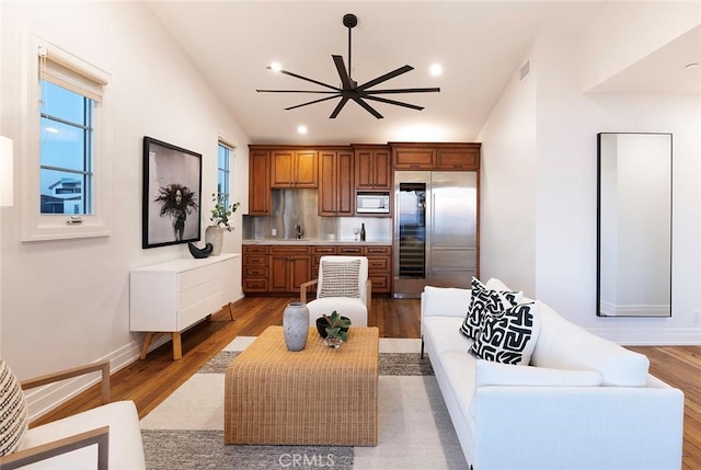 living room with ceiling fan, sink, and wood-type flooring