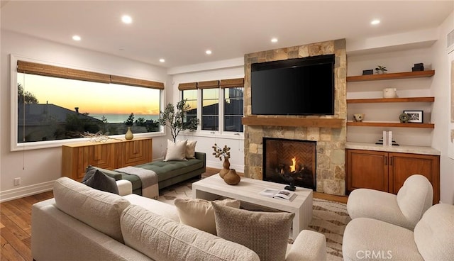 living room featuring built in shelves, light hardwood / wood-style flooring, and a fireplace