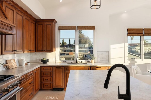 kitchen featuring tasteful backsplash, sink, hanging light fixtures, premium range hood, and high end stove