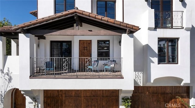 doorway to property with a balcony and a porch