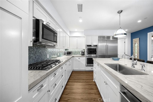 kitchen featuring decorative light fixtures, sink, light stone countertops, appliances with stainless steel finishes, and white cabinets