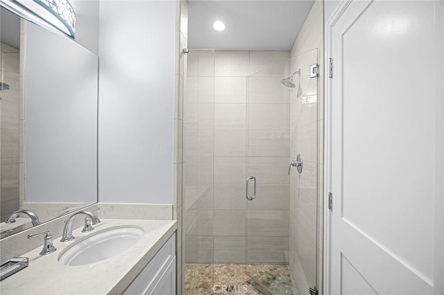 bathroom featuring a shower with shower door and vanity