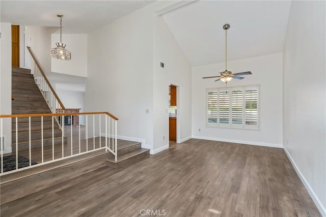 unfurnished living room with ceiling fan with notable chandelier, dark hardwood / wood-style floors, and high vaulted ceiling