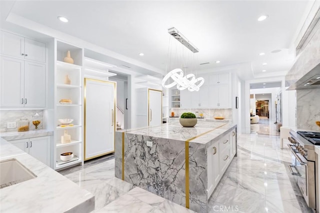 kitchen with pendant lighting, white cabinets, a center island, stainless steel range, and light stone counters