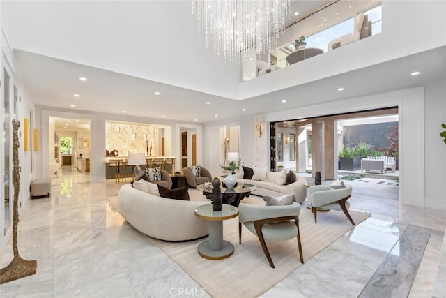 living room featuring a towering ceiling, plenty of natural light, and a chandelier