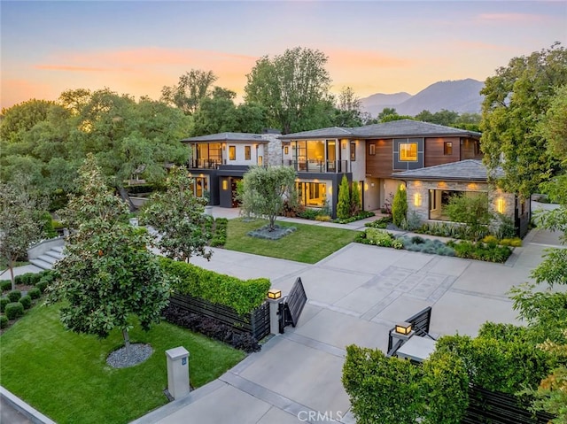 view of front facade with a balcony, a lawn, and a mountain view