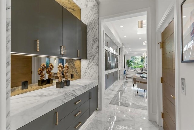 bar with light stone countertops, tasteful backsplash, and gray cabinets