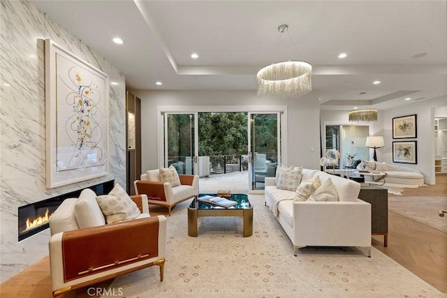 living room with light parquet flooring, a tray ceiling, and a premium fireplace