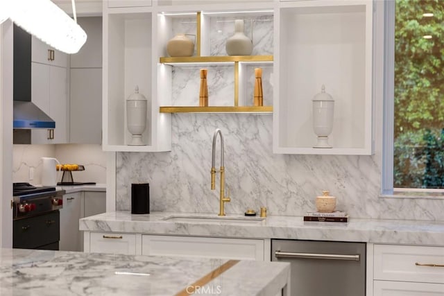 kitchen with stainless steel appliances, backsplash, white cabinets, light stone counters, and sink