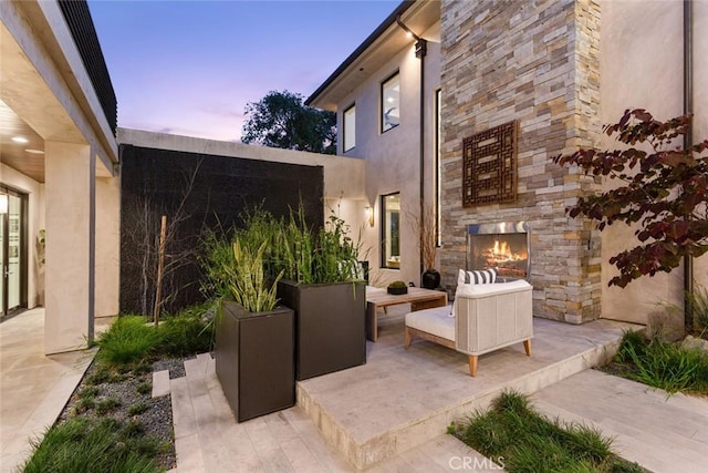 patio terrace at dusk featuring an outdoor living space with a fireplace