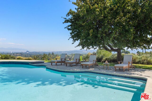 view of swimming pool with a mountain view and a patio