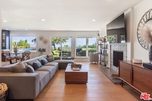 living room featuring a tiled fireplace and light hardwood / wood-style floors