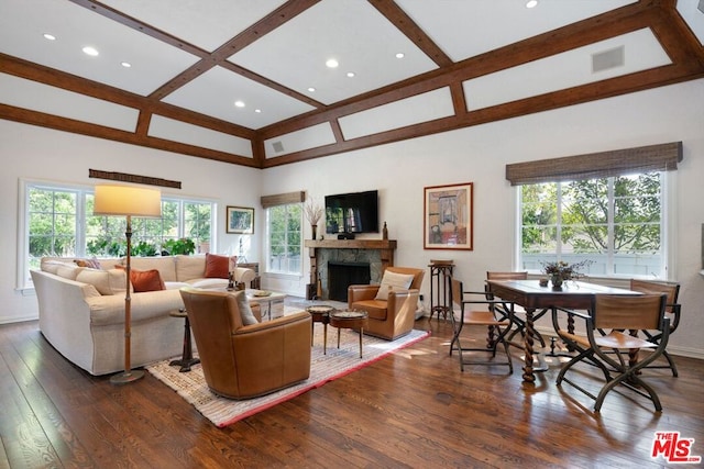 living room with plenty of natural light, a stone fireplace, and coffered ceiling