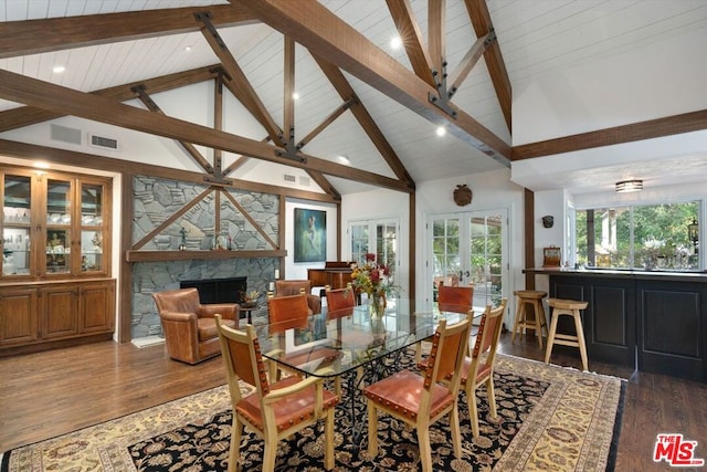 dining room with high vaulted ceiling, french doors, dark hardwood / wood-style flooring, and a stone fireplace