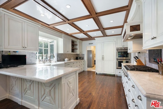 kitchen with kitchen peninsula, sink, coffered ceiling, stainless steel appliances, and white cabinets