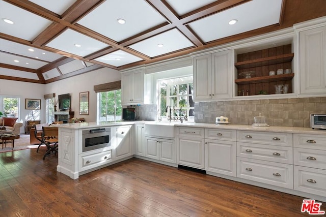 kitchen with white cabinets, sink, backsplash, kitchen peninsula, and built in microwave