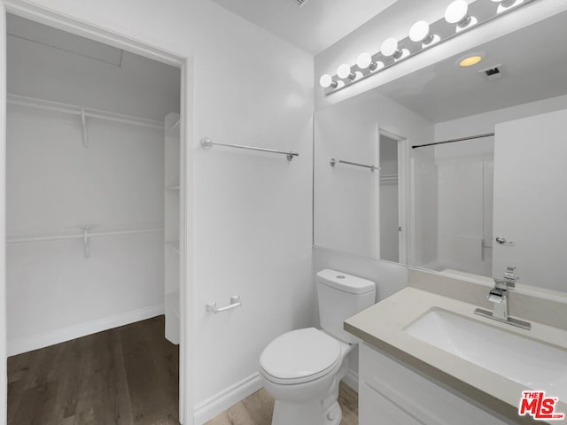 bathroom with toilet, walk in shower, wood-type flooring, and vanity