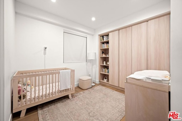 bedroom featuring light hardwood / wood-style floors and a crib