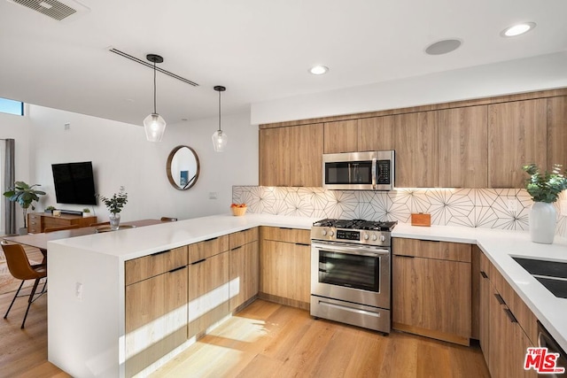 kitchen with light hardwood / wood-style floors, kitchen peninsula, stainless steel appliances, decorative backsplash, and hanging light fixtures