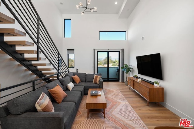 living room featuring a chandelier, light hardwood / wood-style floors, and a towering ceiling