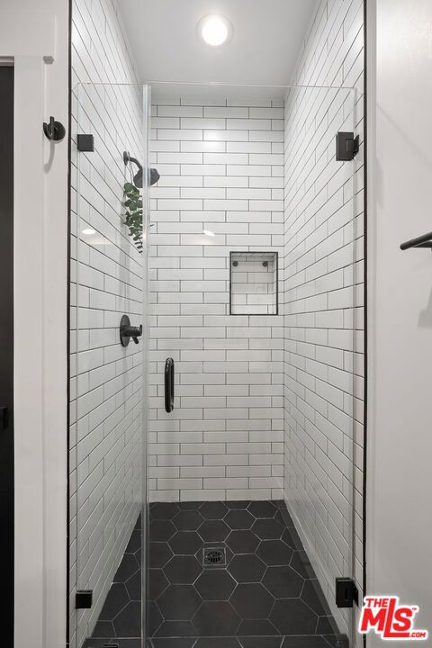 bathroom with a shower with shower door and tile patterned flooring