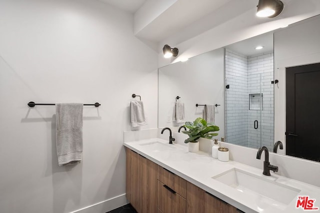 bathroom featuring a shower with shower door and vanity