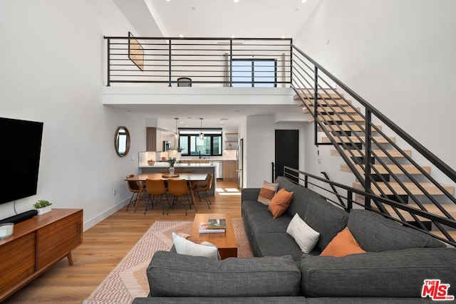 living room featuring light wood-type flooring and a high ceiling