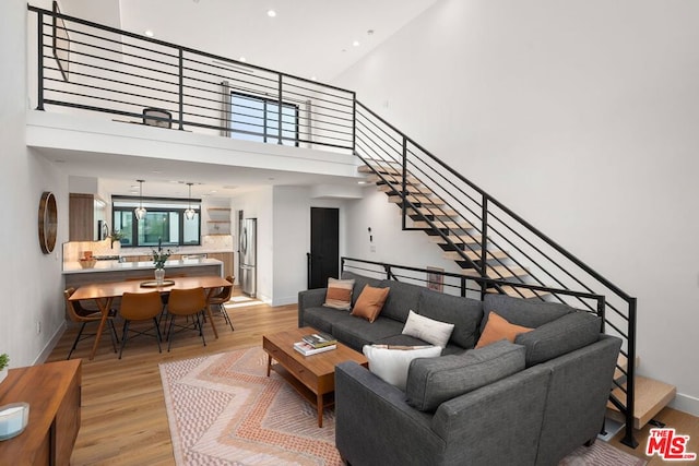 living room featuring light wood-type flooring and a towering ceiling