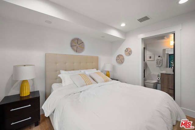 bedroom with dark hardwood / wood-style flooring and ensuite bath