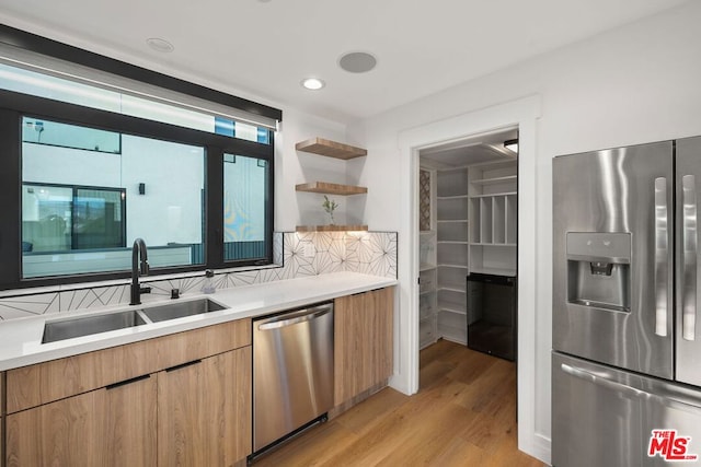 kitchen featuring sink, appliances with stainless steel finishes, light hardwood / wood-style flooring, and tasteful backsplash