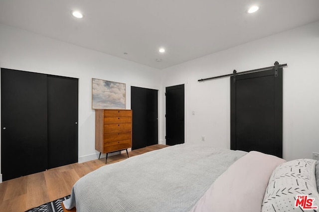 bedroom with a barn door and light hardwood / wood-style flooring