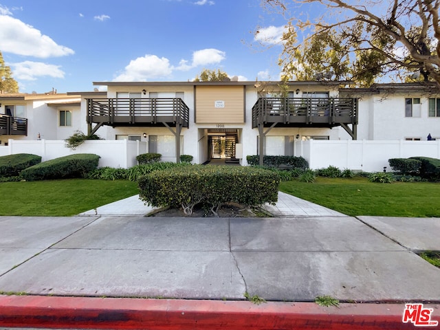 view of front facade with a balcony and a front lawn