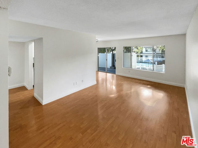 unfurnished room featuring hardwood / wood-style flooring and a textured ceiling