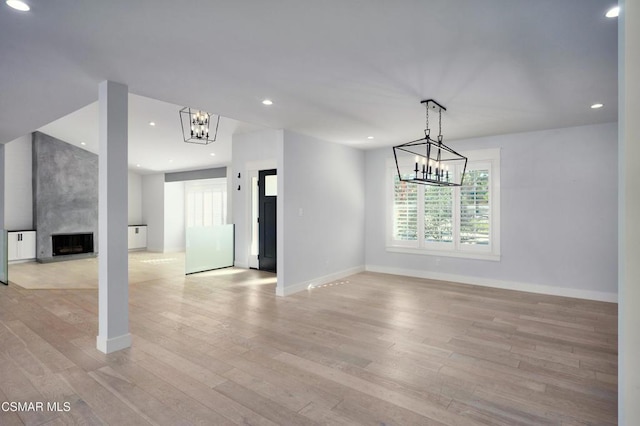 interior space featuring light wood-type flooring, an inviting chandelier, and a premium fireplace