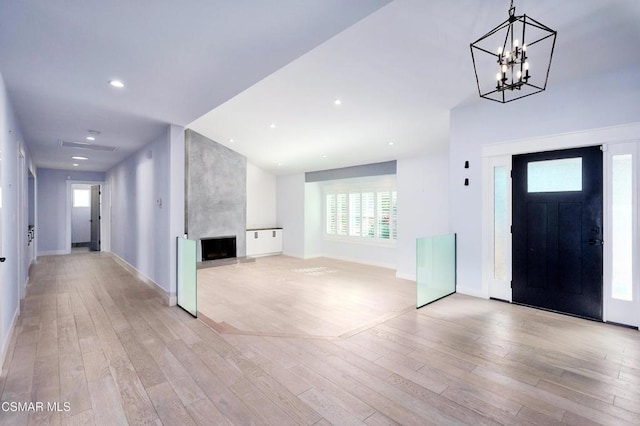 entrance foyer featuring a large fireplace, light hardwood / wood-style flooring, and a notable chandelier