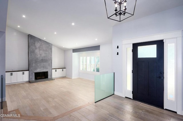 entrance foyer featuring a notable chandelier, a large fireplace, and light hardwood / wood-style flooring