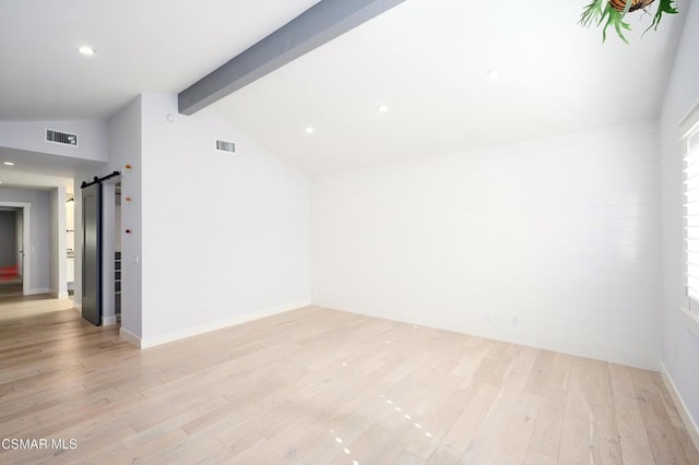 unfurnished room with a barn door, lofted ceiling with beams, and light hardwood / wood-style floors