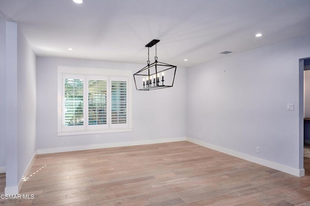 unfurnished dining area with a chandelier and light hardwood / wood-style flooring