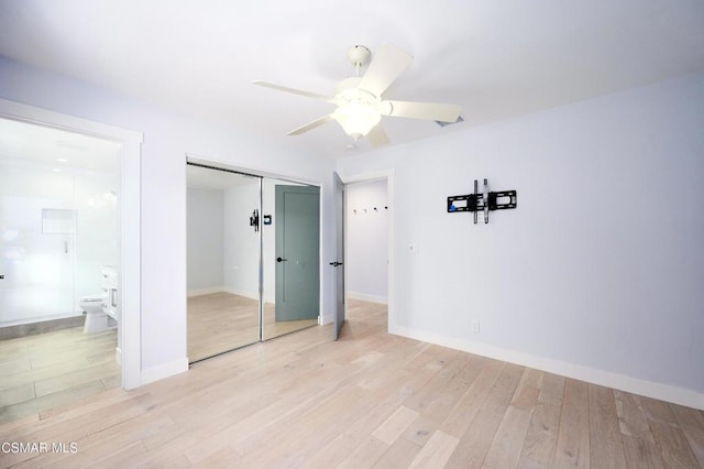 unfurnished bedroom featuring ceiling fan, a closet, ensuite bath, and light hardwood / wood-style flooring