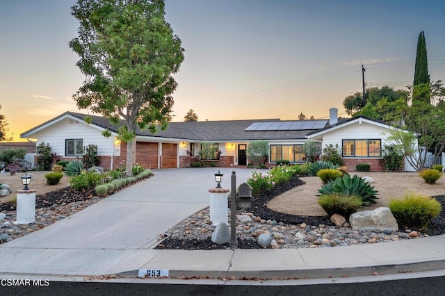 ranch-style house featuring a garage and solar panels