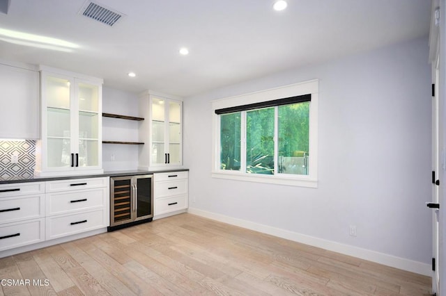 bar featuring white cabinets, tasteful backsplash, beverage cooler, and light hardwood / wood-style floors