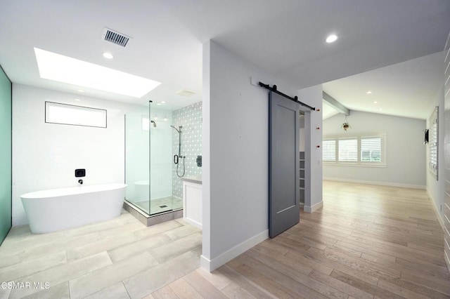 bathroom featuring separate shower and tub, vaulted ceiling with skylight, and hardwood / wood-style flooring