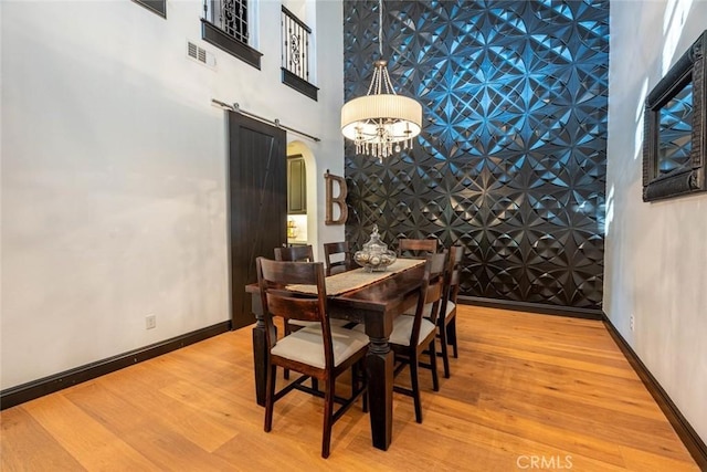 dining area with a chandelier, light hardwood / wood-style flooring, and a barn door