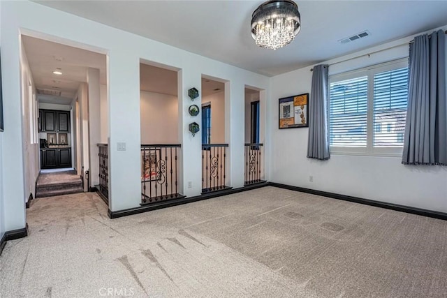 carpeted spare room with an inviting chandelier