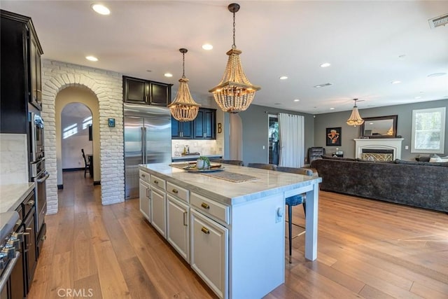 kitchen with tasteful backsplash, a center island, white cabinetry, stainless steel appliances, and light stone counters