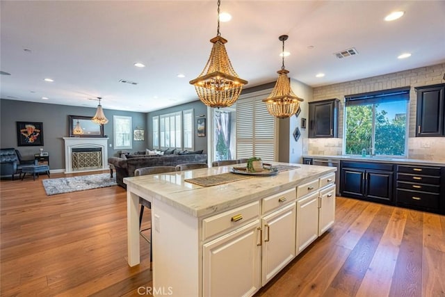 kitchen featuring light hardwood / wood-style floors, a breakfast bar area, backsplash, white cabinets, and a center island