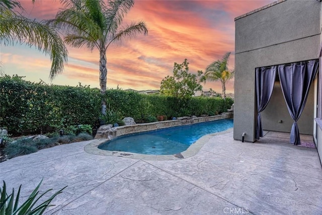 pool at dusk featuring pool water feature and a patio