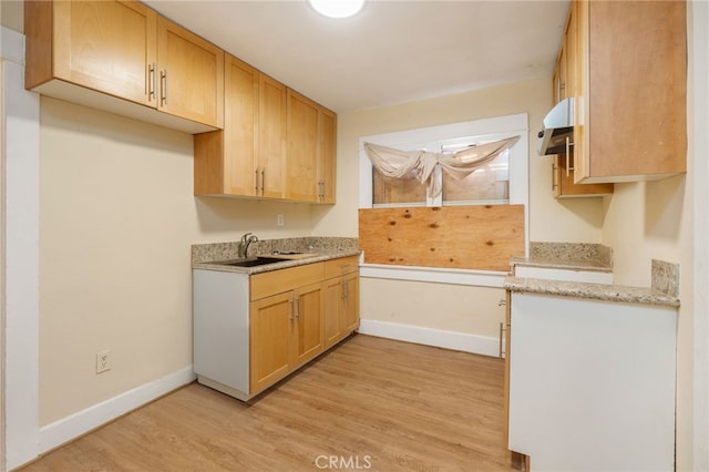 kitchen with extractor fan, light wood-type flooring, sink, and light brown cabinets