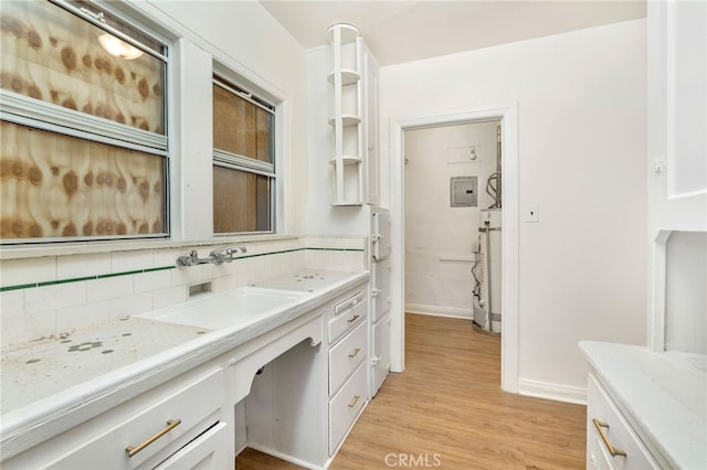 bathroom featuring water heater, vanity, decorative backsplash, hardwood / wood-style flooring, and electric panel